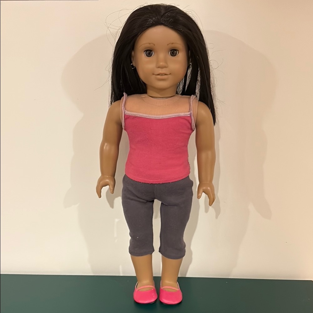 Pre-owned American Girl doll w 2 outfits and small hoop earrings.